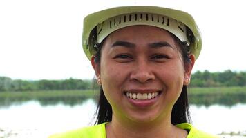 Portrait of a female environmental engineer smiling proudly against a power plant, high-voltage pole and reservoir in the background. Energy, ecology and environment concept video