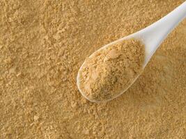 Nutritional yeast background. Nutritional inactive yeast in white spoon. Copy space. Top view. Nutritional yeast is vegetarian superfood with cheese flavor, for healthy diet photo