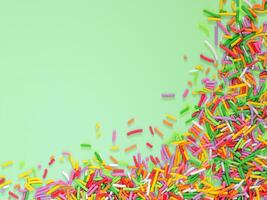 Border frame of colorful sprinkles on green background photo