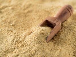 Nutritional yeast background. Nutritional inactive yeast with small wooden scoop. Copy space. Nutritional yeast is vegetarian superfood with cheese flavor, for healthy diet photo
