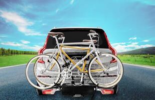 Back view gray suv car and bicycle on the rear rack with highway road view background photo