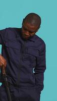 Vertical Portrait of security agent removing baton from belt, using it to secure assigned post, studio background. African american guardian pointing finger to truncheon, handling security breaches, camera B video