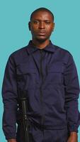 Vertical Portrait of smiling security agent securing assigned post, isolated against studio background. African american guardian prepared to handle security breaches and diffuse tense situations, camera B video