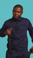 Vertical Portrait of security guard overseeing premises, turning on flashlight and preparing baton to detain suspects. Private law enforcement worker using lantern and truncheon gear, studio backdrop, camera B video