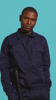 Vertical Portrait of security guard doing thumbs down sign gesturing, denying access while overseeing premises. Private law enforcement worker doing negative hand gesture, studio backdrop, camera B video