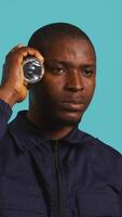 Vertical Headshot portrait of security employee tasked with evicting trespassers, turning on flashlight. Close up shot of patrolling agent using lantern, spotting intruders, studio background, camera B video