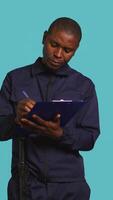 Vertical Portrait of security agent holding clipboard, taking notes, receiving orders to secure assigned post, studio background. Guardian maintains logs of observations, handling security breaches, camera B video