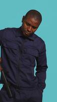 Vertical Security guard smacking hand with baton, intimidating suspects. Portrait of bodyguard showing truncheon, threatening to subdue criminals, shaking head, studio background, camera B video