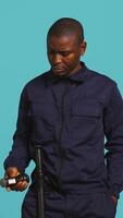 Vertical Portrait of security guard catching intruder with flashlight while overseeing premises. Private law enforcement worker calls over trespasser after detecting him with lantern, studio backdrop, camera B video