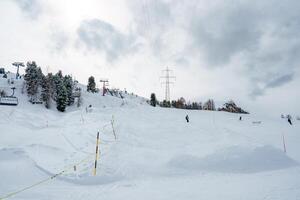 Winter scene at a ski resort skiers on snow covered slope with ski lift in background. Overcast sky and trees dusted with snow. Activity on the mountain. photo