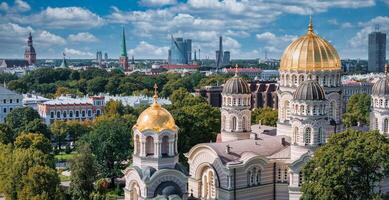 The Nativity of Christ Cathedral in Riga, Latvia. Byzantine-styled Orthodox cathedral, the largest in the Baltic region, with golden colored dome, polished gilded cupolas gleaming through the trees photo