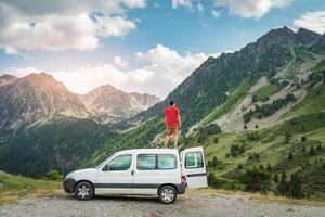 Young man enjoying nature on top of his camper van. photo