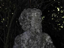 An old statue of a faun in a garden photo
