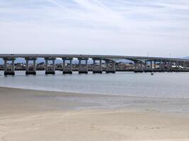 An abandoned chair in front of the Barra bridge durong Low tide in The lagoon Ria de Aveiro photo