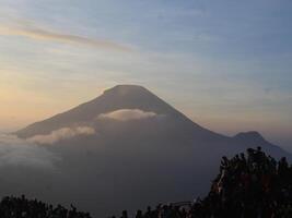 view of the sunrise on Mount Dieng with clouds covering the mountain photo