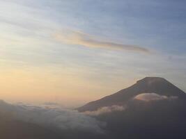 view of the sunrise on Mount Dieng with clouds covering the mountain photo