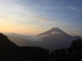 view of the sunrise on Mount Dieng with clouds covering the mountain photo