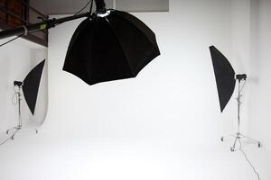 photo studio inside, white background, several racks with light sources, cyclorama, softboxes, pulsed light, flashes