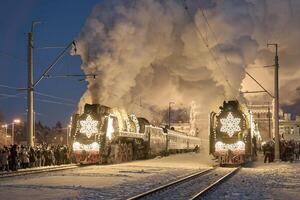 Russia, Peterhof, 07 January 2024. Two Santa Claus Trains leave the magically decorated building of the New Peterhof station, huge steam clubs, many people, incredible lighting photo