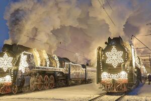 Russia, Peterhof, 07 January 2024. Two Santa Claus Trains leave the magically decorated building of the New Peterhof station, huge steam clubs, many people, incredible lighting photo