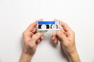 White and blue cassette in male hands on a white background, top view. Mock-up for an inscription on a magnetic cassette, an object of old luxury photo