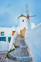 Old greek windmill on Santorini island in Oia town with stairs in street. Santorini, Greece photo