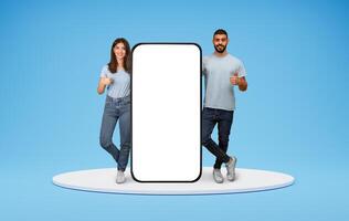 Mobile Mockup. Happy Arabic Couple Standing Near Huge Blank Smartphone And Showing Thumbs Up, Smiling Middle Eastern Man And Woman Recommending New App Or Website On Blue Background, Collage, Mockup photo