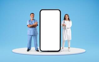 Middle aged professional team doctors standing on platform, pointing at huge phone with white empty screen, recommending telehealth mobile app, blue background, blank space. E-health, telemedicine photo