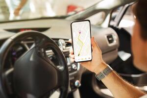 Man driver sitting in front sit in the car, holding mobile phone with map gps navigation on gadget screen, unrecognizable guy checking location destination, travelling alone by auto photo