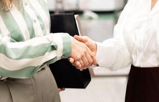 Business Partnership. Cropped Shot Of Two Businesswomen Shaking Hands In Agreement And Cooperation, During Meeting For Job Interview At Modern Office Indoors. Closeup Of Handshake Greeting Gesture photo