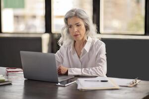 Hispanic Businesswoman Using Laptop Managing Budgets Online And Communicating Sending Emails In Modern Office, Sitting At Workplace Desk With Computer. Business And Internet Technology photo