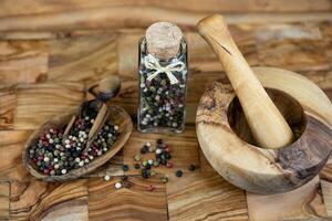 a stack of peppercorns on olive wood photo