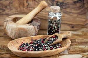 a stack of peppercorns on olive wood photo