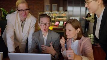 A group of confident businesswomen in a business uniform gathered around a laptop and a girl speaker in a gray suit presenting their work and ideas while working in a modern office video