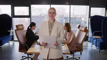 Portrait Confident middle-aged businesswoman with glasses in a white suit holding a sheet of paper in her hands while working in the office Near the table video