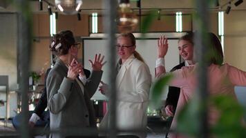 Side view of a group of happy businesswomen in business clothes dancing while celebrating their Victory and success while working in a modern office video