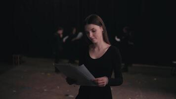 Portrait of a confident girl actor in a black suit who revises her text and script of the work during a rehearsal and preparation for a performance on stage in the theater video