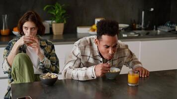 Black brunette man He didn't like the cereal with juice during his breakfast and he spits it straight into his plate during breakfast with his young adult brunette girlfriend with a bob hairstyle she video