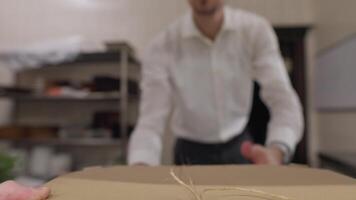 First-person view of a guy handing over a finished order in a cardboard package to a waiter in a restaurant for online delivery. The finished order in a restaurant in a cardboard package is given to video