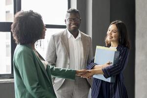 Recruitment And Career Growth. Diverse Colleagues Women Shaking Hands Standing With Manager Man, Team Welcoming New Employee In Office Indoor. Business Networking And Communication. Selective Focus photo