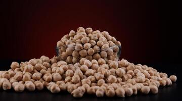 Glass cup with chickpeas on a beautiful illuminated red background. photo