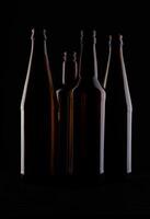 Several beer bottles on a dark background in backlight. photo
