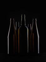 Several beer bottles on a dark background in backlight. photo