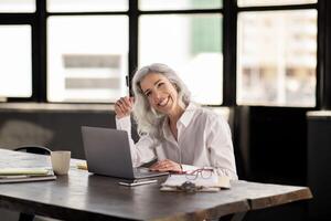 Professional Entrepreneurship. Smiling Business Woman Sitting At Laptop Working Online In Office Interior. Manager Enjoying Corporate Routine Using Computer At Workplace, Looking Aside photo