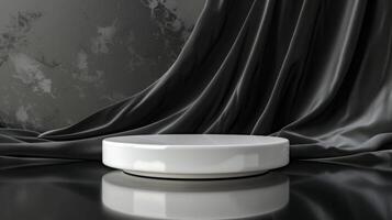 A shiny white round pedestal sits on a black reflective surface, complemented by a background of draped gray silk fabric. photo