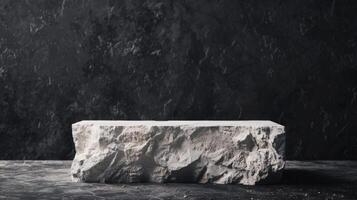 A large, rough-cut marble block rests on a dark surface with a black textured wall backdrop, lit by soft studio lighting. photo