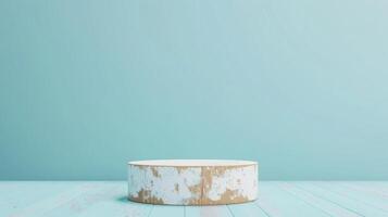 A rustic, white-washed wooden pedestal stands on a weathered blue plank floor against a matching blue background in a brightly lit studio setting. photo