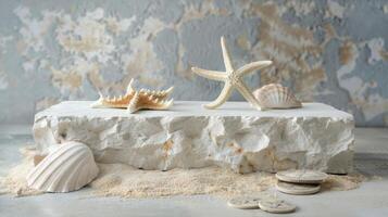 Various seashells and a starfish are artfully arranged on a white rock display, surrounded by sand with a textured, neutral backdrop. photo