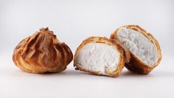 Cut in half and whole porophytole with white cream isolated on a white background. Eclair with cream. photo