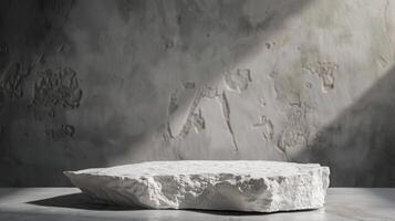 A white stone rests on a gray surface, illuminated by sunlight streaming through a weathered concrete wall, creating a serene and minimalist scene in the afternoon. photo